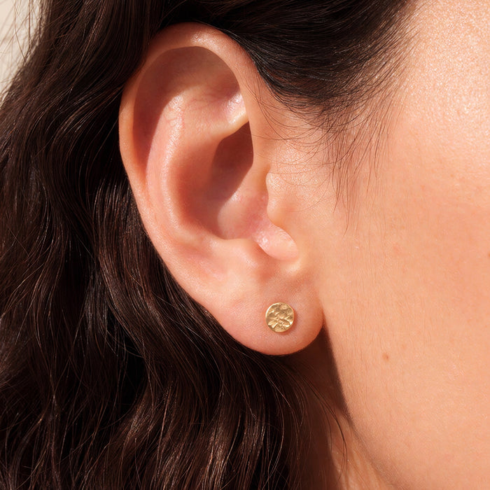 Hammered dot stud earrings 5mm small circle earrings solid 14k gold on model