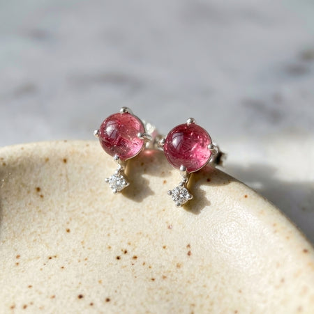Sterling silver pink tourmaline celestial stud earrings with tiny clear topaz accent stones leaning on off white ceramic jewelry dish