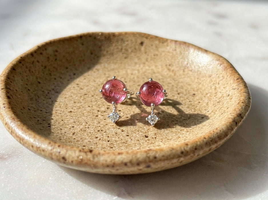 Sterling silver pink tourmaline celestial stud earrings with tiny clear topaz accent stones on light beige ceramic jewelry dish wide view