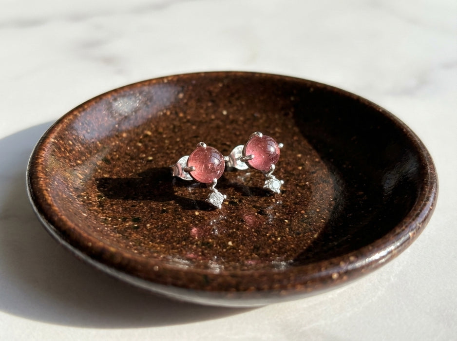 Sterling silver pink tourmaline celestial stud earrings with tiny clear topaz accent stones on ceramic jewelry dish wide view