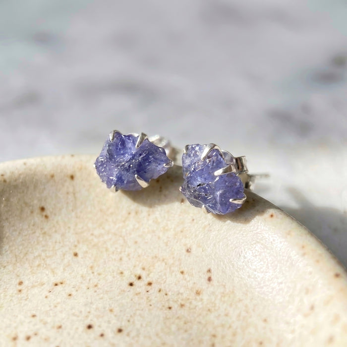 Raw tanzanite blue lavender statement stud earrings with raw natural crystals rough blue stone bold and colorful healing crystal stud earrings on ceramic jewelry dish