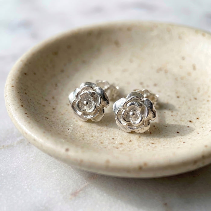 Vintage sterling silver rose stud earrings on ceramic jewelry dish